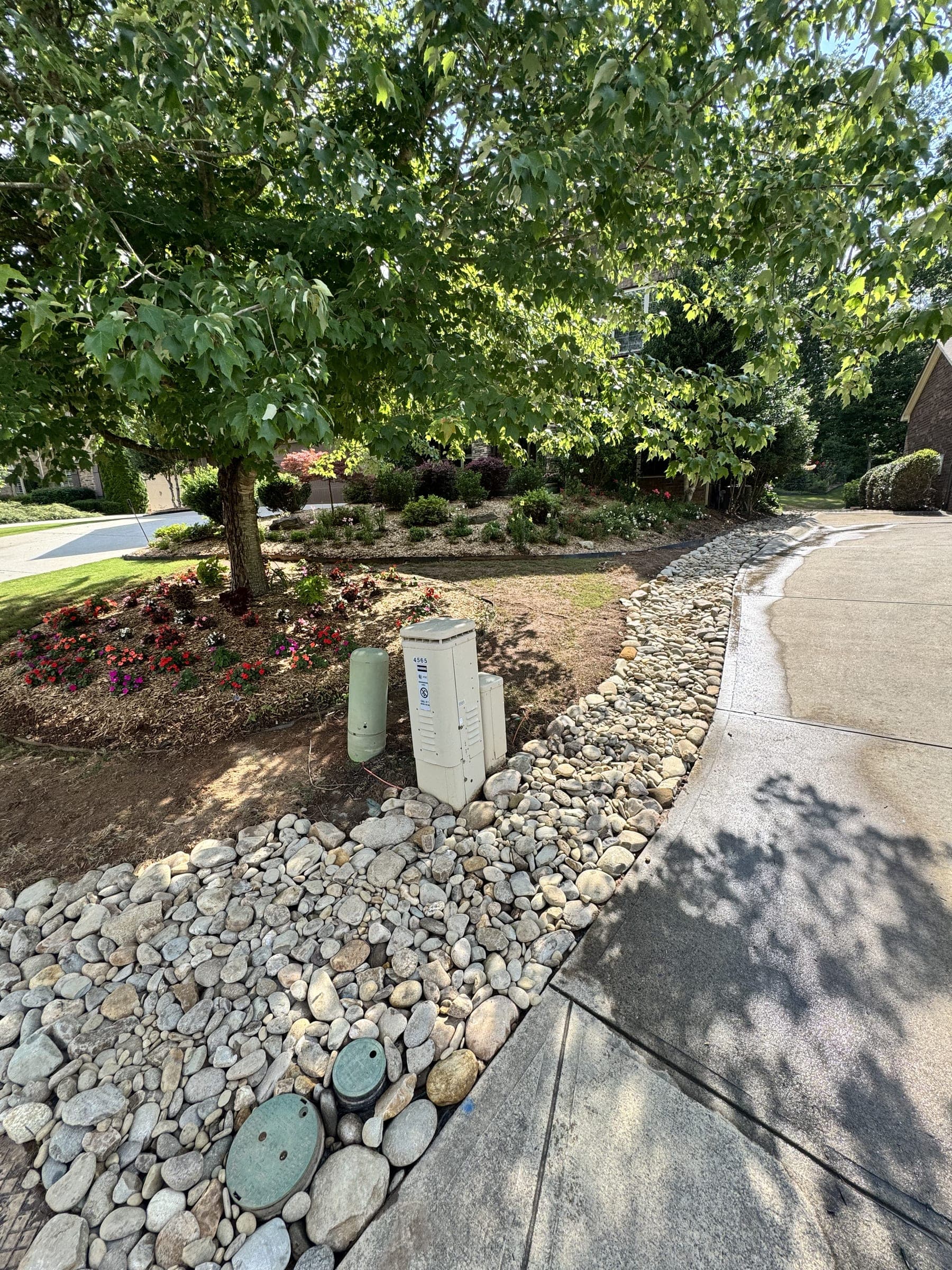 Rock-lined drainage path beside a concrete walk