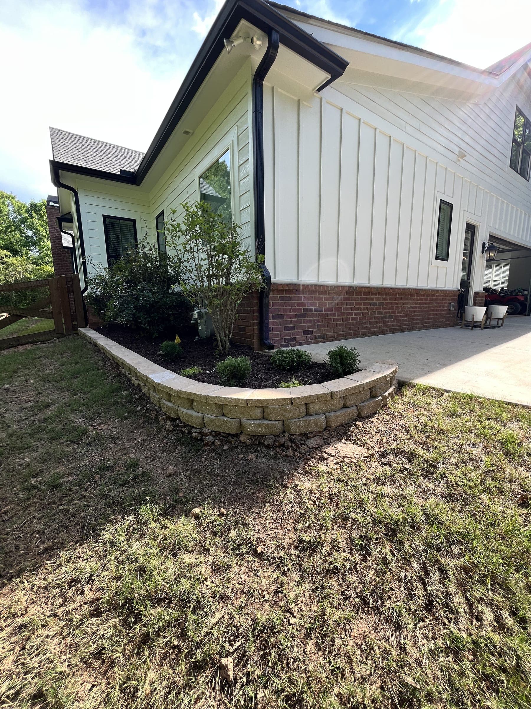 Block retaining wall edging a planting bed beside a home