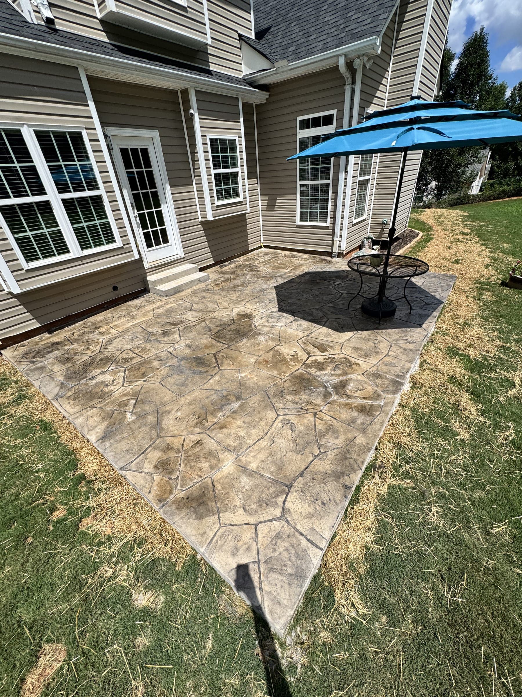 Flagstone patio with an umbrella outside a home's back doors