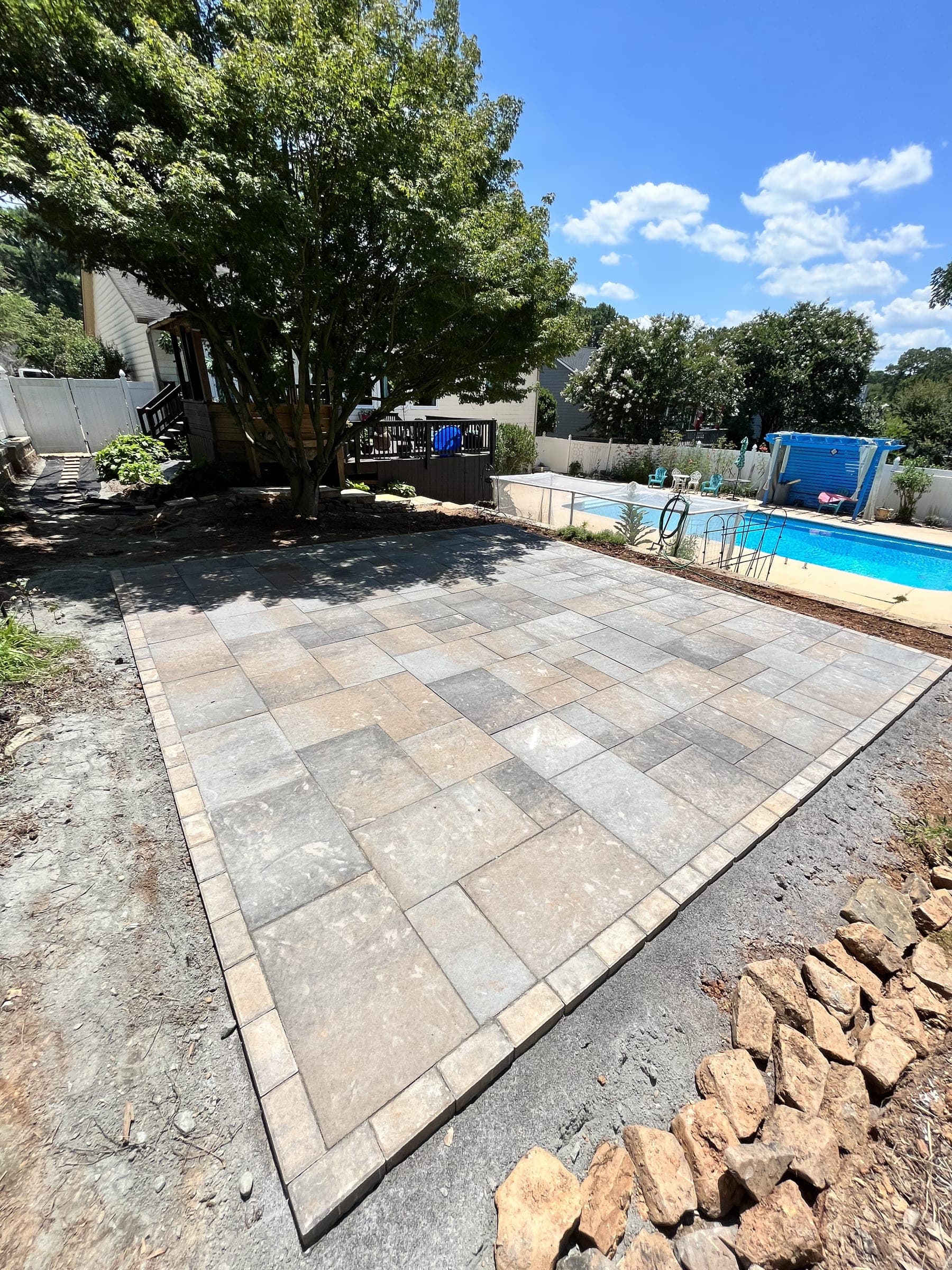 New paver patio with a border course beside a backyard pool