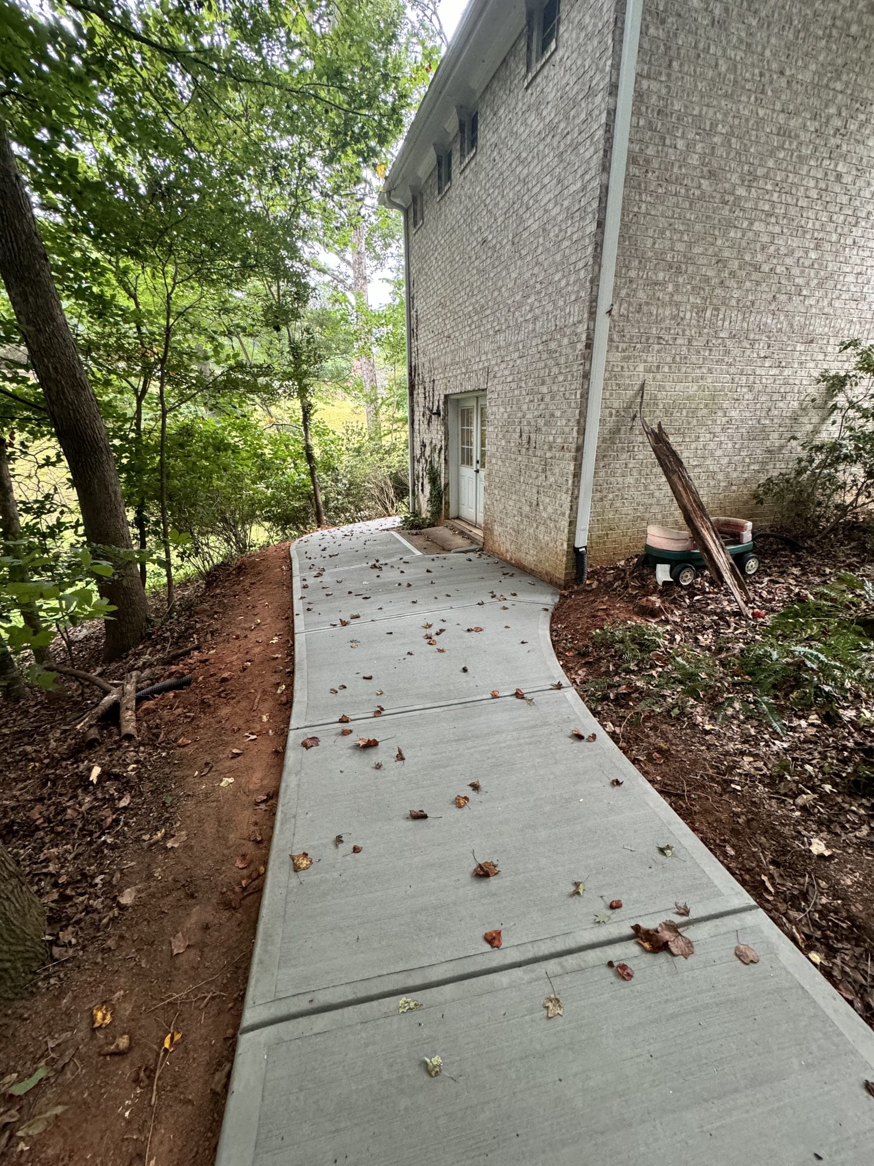 Broom-finish concrete walkway between a home and a wooded lot