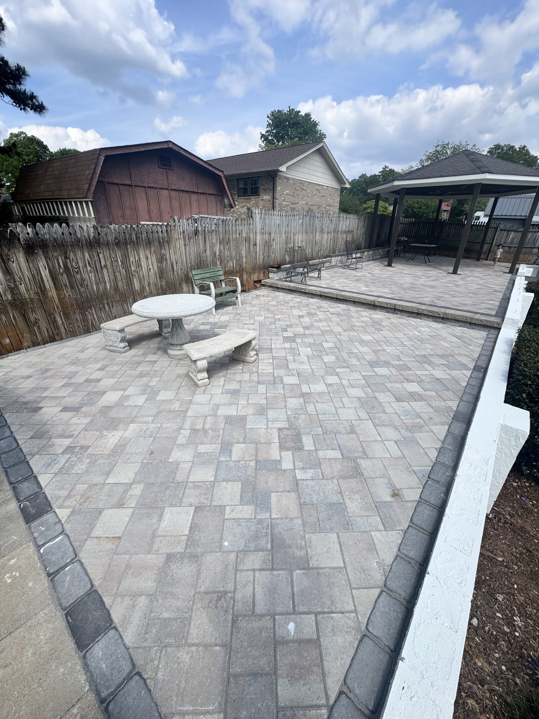 Paver patio with a border band beside a fenced yard
