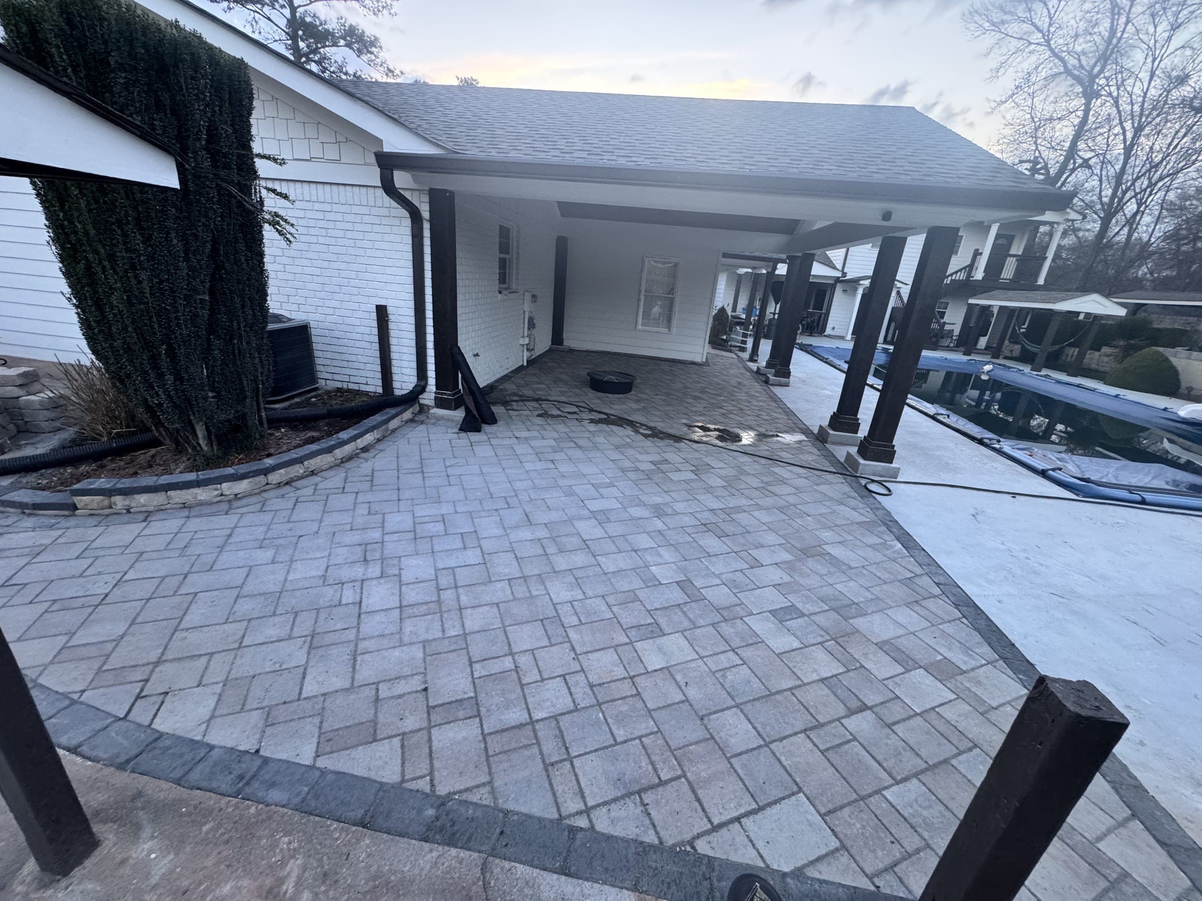 Paver patio and driveway apron beside a covered carport
