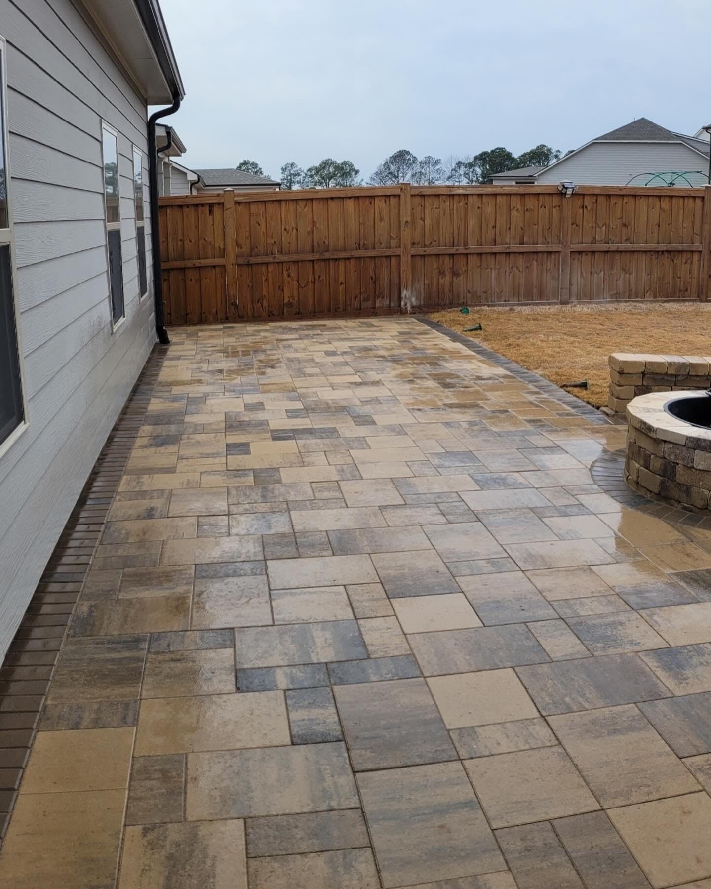 Paver patio with a stone fire pit and seat wall